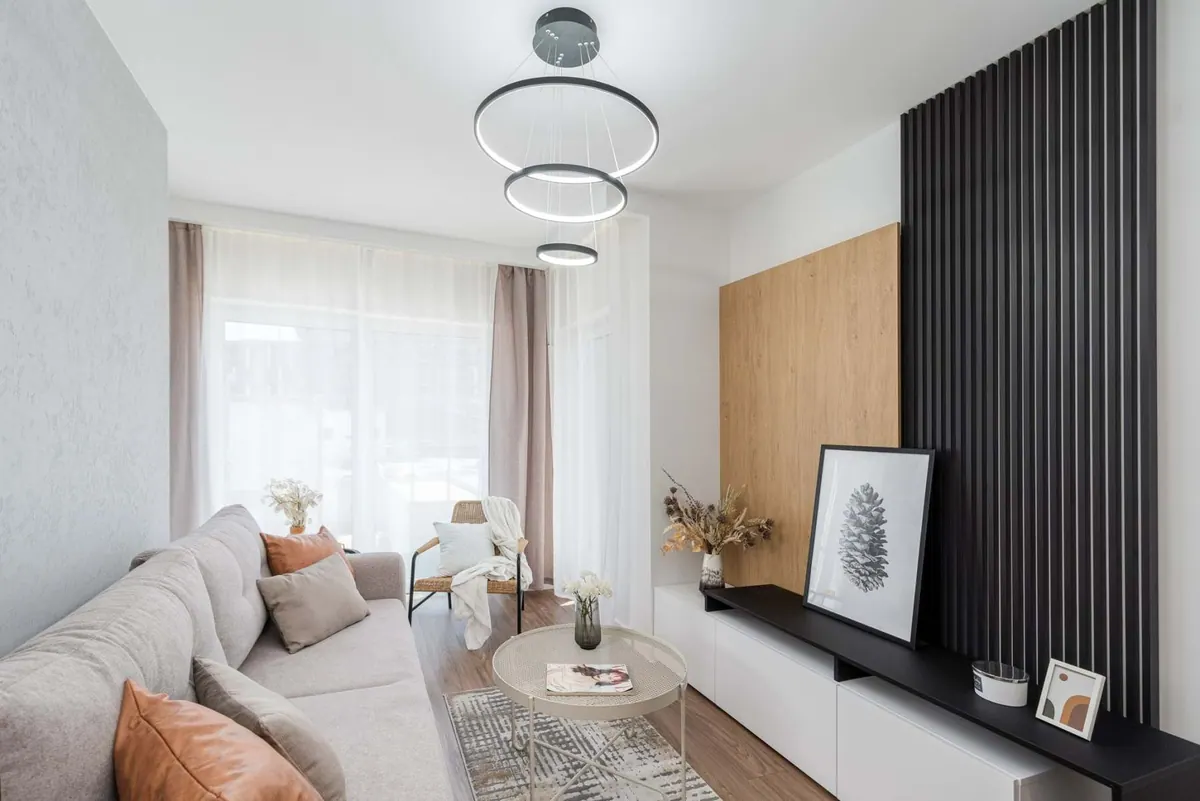 Wohnzimmer mit schwarzer Lamellenwand und niedrigem, weißem TV-Lowboard nach Maß
